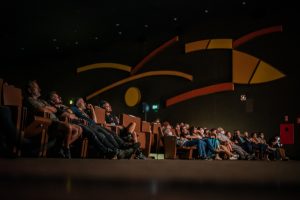Sala do Cine Brasília, mostra plateia nas poltronas e, ao fundo, painel do Athos Bulcão