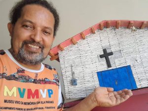 Homem negro segura escultura de casa do Paranoá