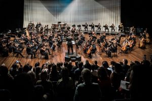 Orquestra Sinfônica se apresentando no palco do Teatro Plínio Marcos