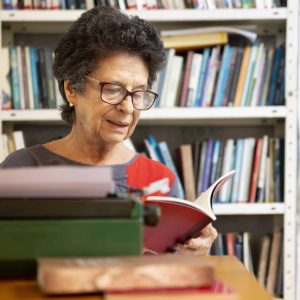 Mulher de óculos, lendo livro em uma biblioteca