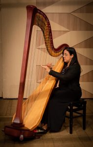 Mulher sentada toca sua harpa