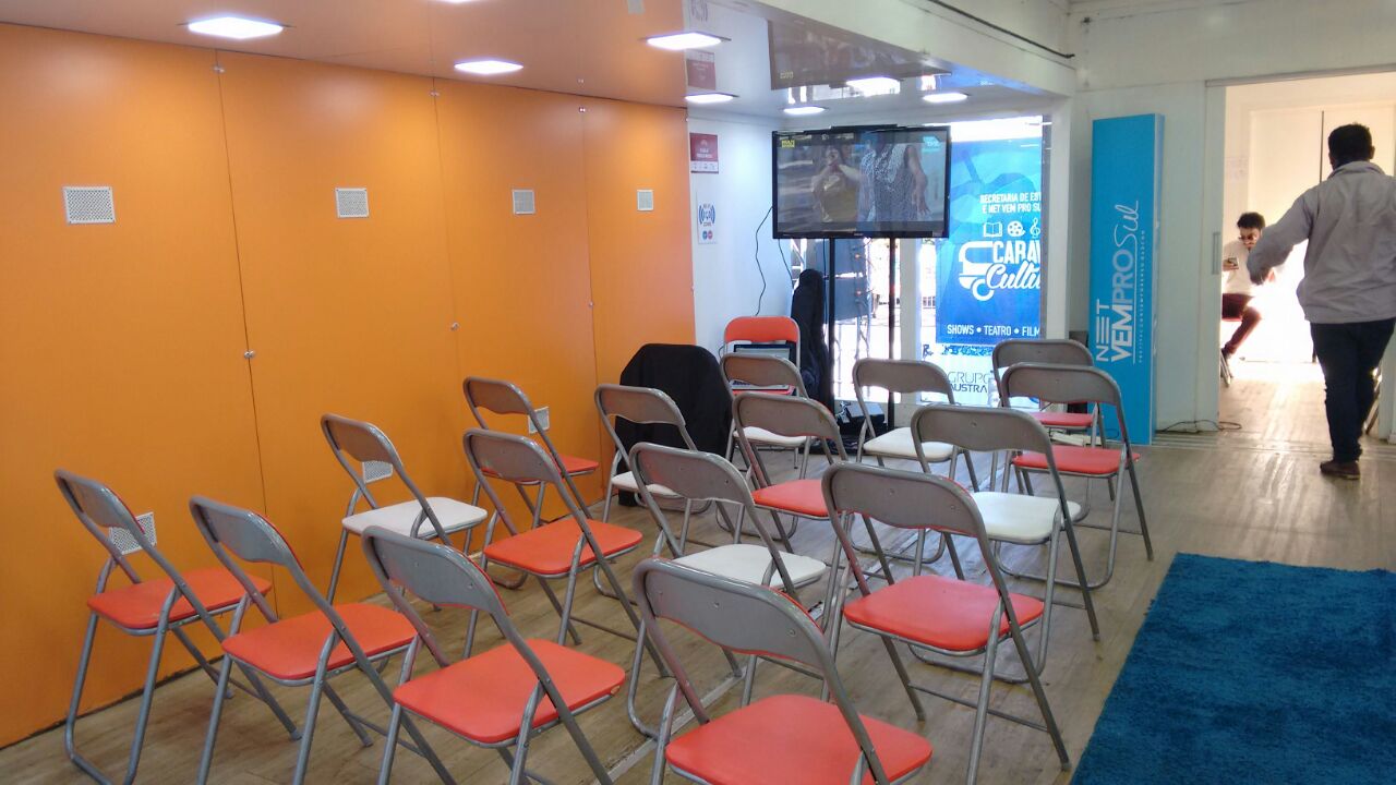 Cadeiras dispostas em frente a uma televisão em sala de aula
