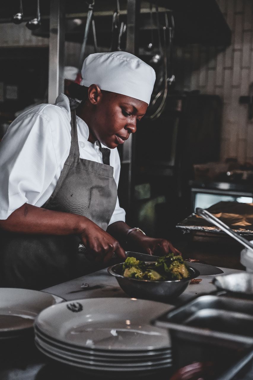 Pessoa com roupa de chef de cozinha cortando alimentos