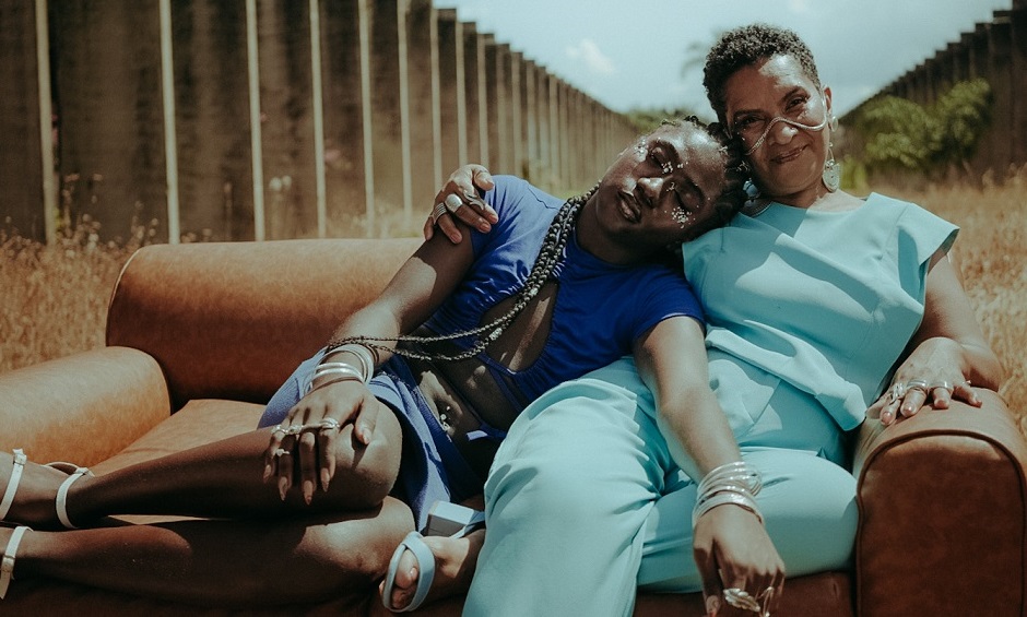 Frame do filme Rumo, com duas mulheres negras de roupa azul sentadas em um sofá