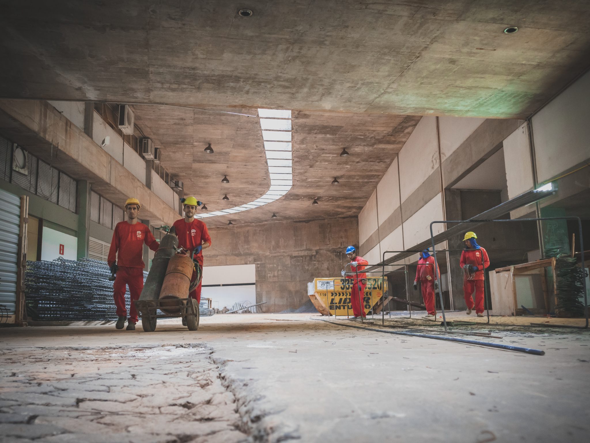 Homens trajando roupas vermelhas num espaço de obras