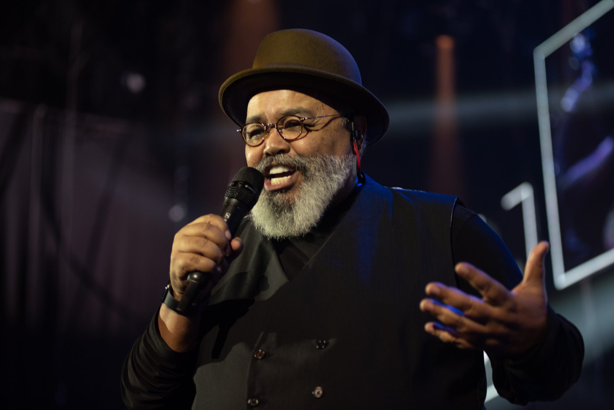 Jorge Aragão segurando o microfone no palco, sorrindo