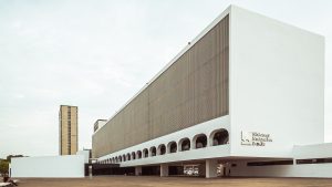 Fachada lateral da Biblioteca Nacional de Brasília, edifício branco com arcos e sob pilotis
