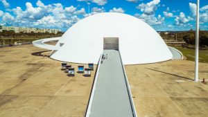 Foto aérea, mostra a rampa do museu e seu edifício, em formato de semiesfera