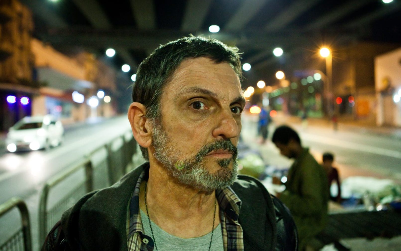Homem em primeiro plano, no meio da cidade, olhando para o horizonte
