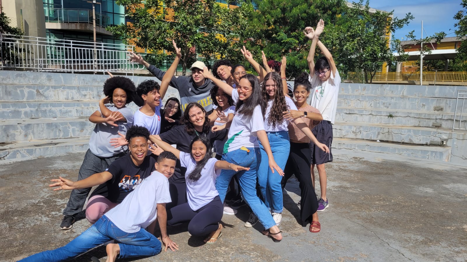 Imagem da professora Ana Carolina Mendes cercada por alunos sorridentes em posição de dança