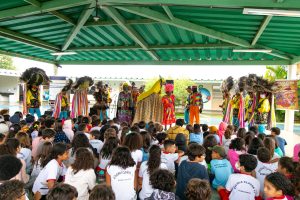 Pessoas com trajes tradicionais performam para crianças em escola