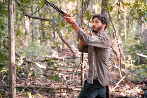Imagem de um guerrilheiro na floresta epunhando uma metralhadora